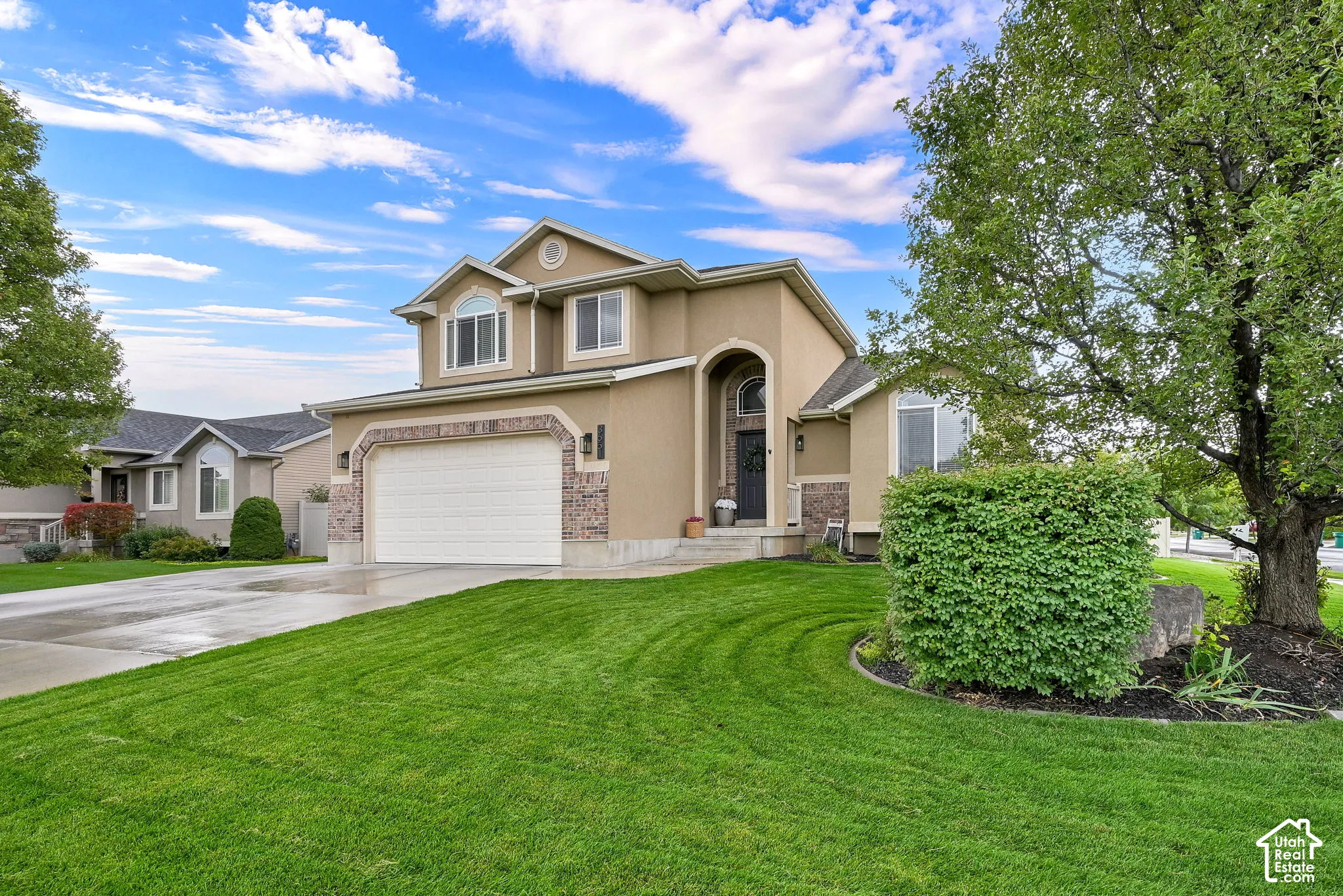 Two-story stucco exterior with stone accents, arched entryway, and mature landscaping