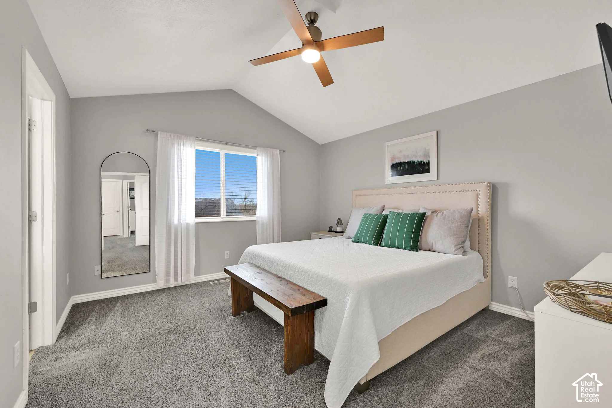 Vaulted ceiling with an attached ceiling fan, large window with blinds, and carpeting