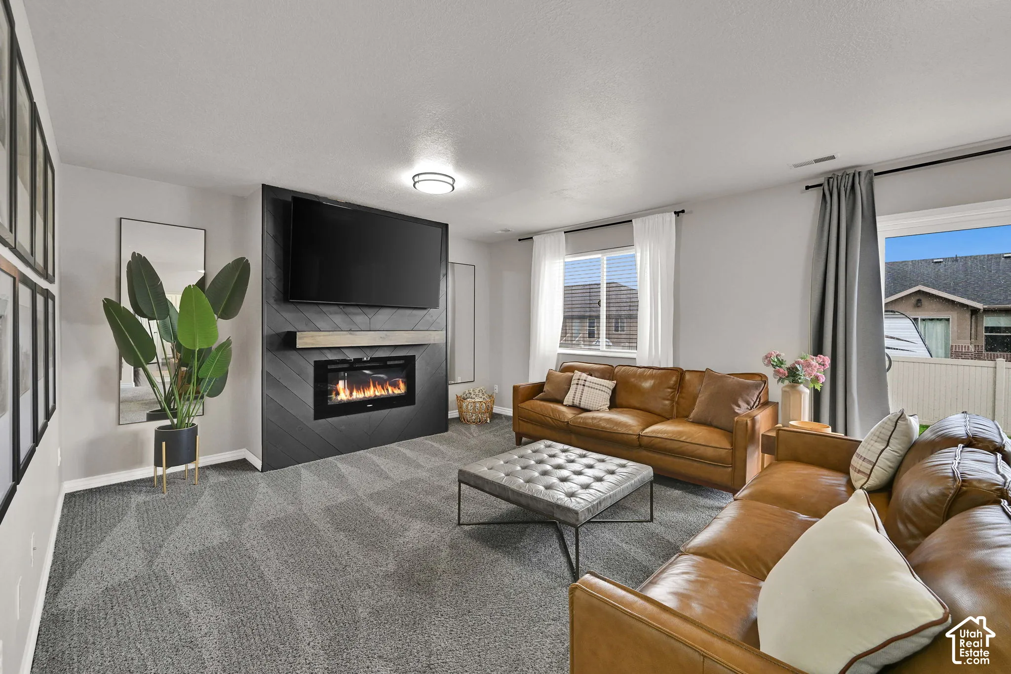 Modern living area featuring a fireplace with a chevron-patterned surround, a natural wood-finish mantel, and carpeting