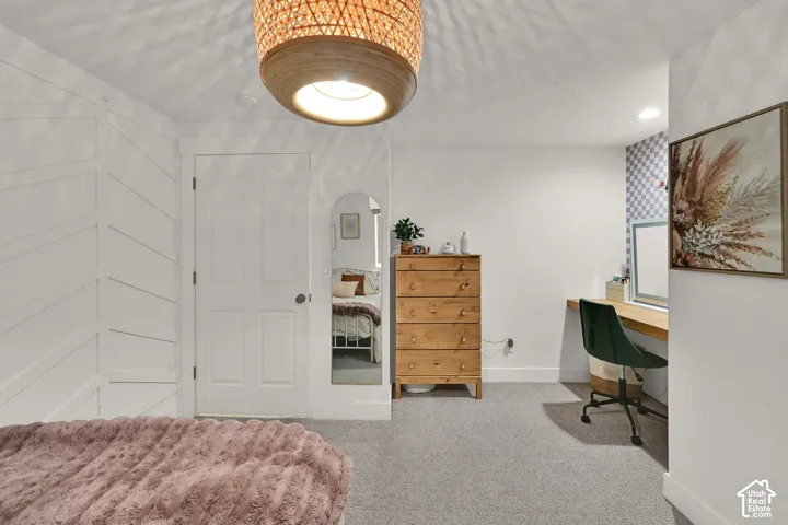 White paneled accent wall, woven ceiling light fixture, and a built-in wood-finish desk