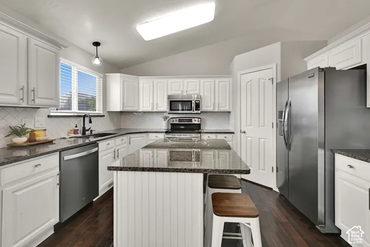 White cabinetry with brushed nickel hardware, dark wood flooring, stainless steel appliances, granite countertops, and white tile backsplash
