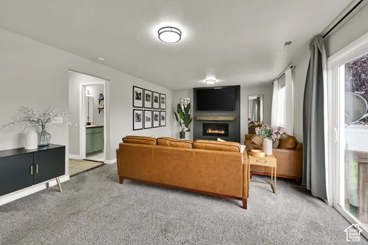 Carpeted living area featuring a built-in fireplace with a wood mantel, a sliding glass door, and recessed lighting