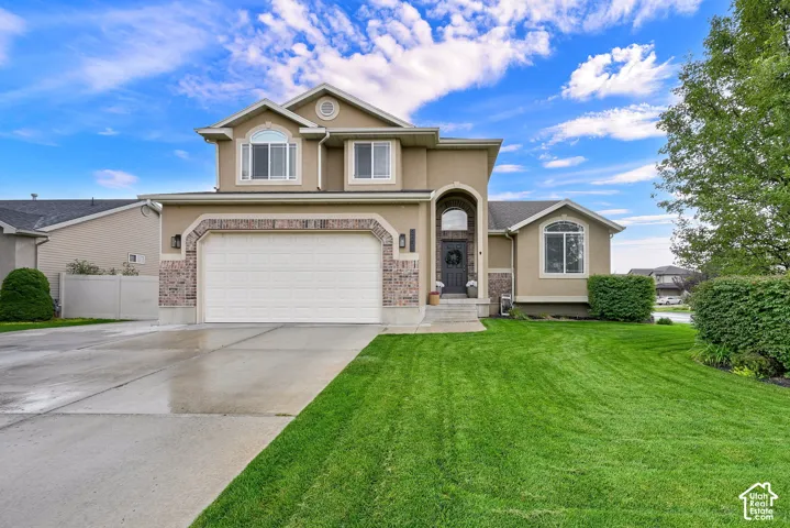 Two-story stucco and brick exterior, arched entryway, bay window, two-car garage, RV pad, and a lush front lawn