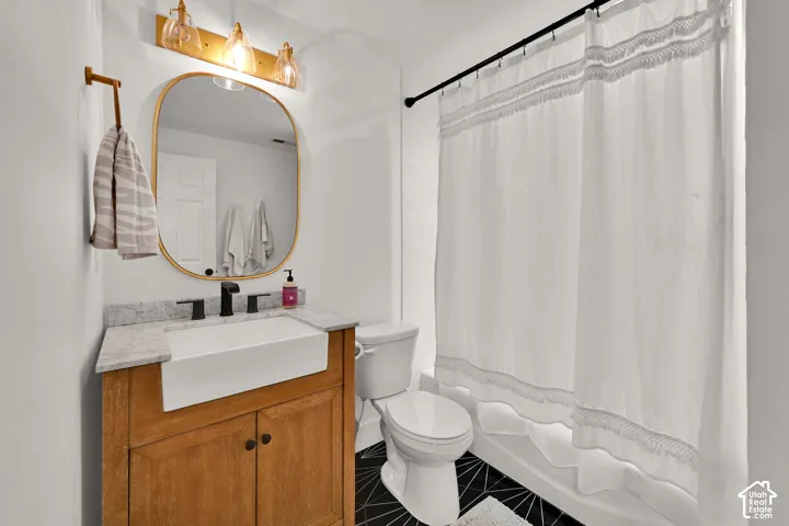 Wood-finish vanity with a farmhouse-style sink, stone countertop, and matte black faucet