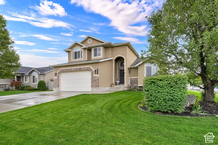 Two-story stucco exterior with stone accents, arched entryway, and mature landscaping