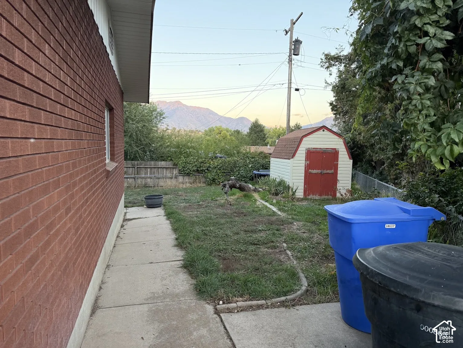 Brick exterior with a window, concrete pathway, and a storage shed