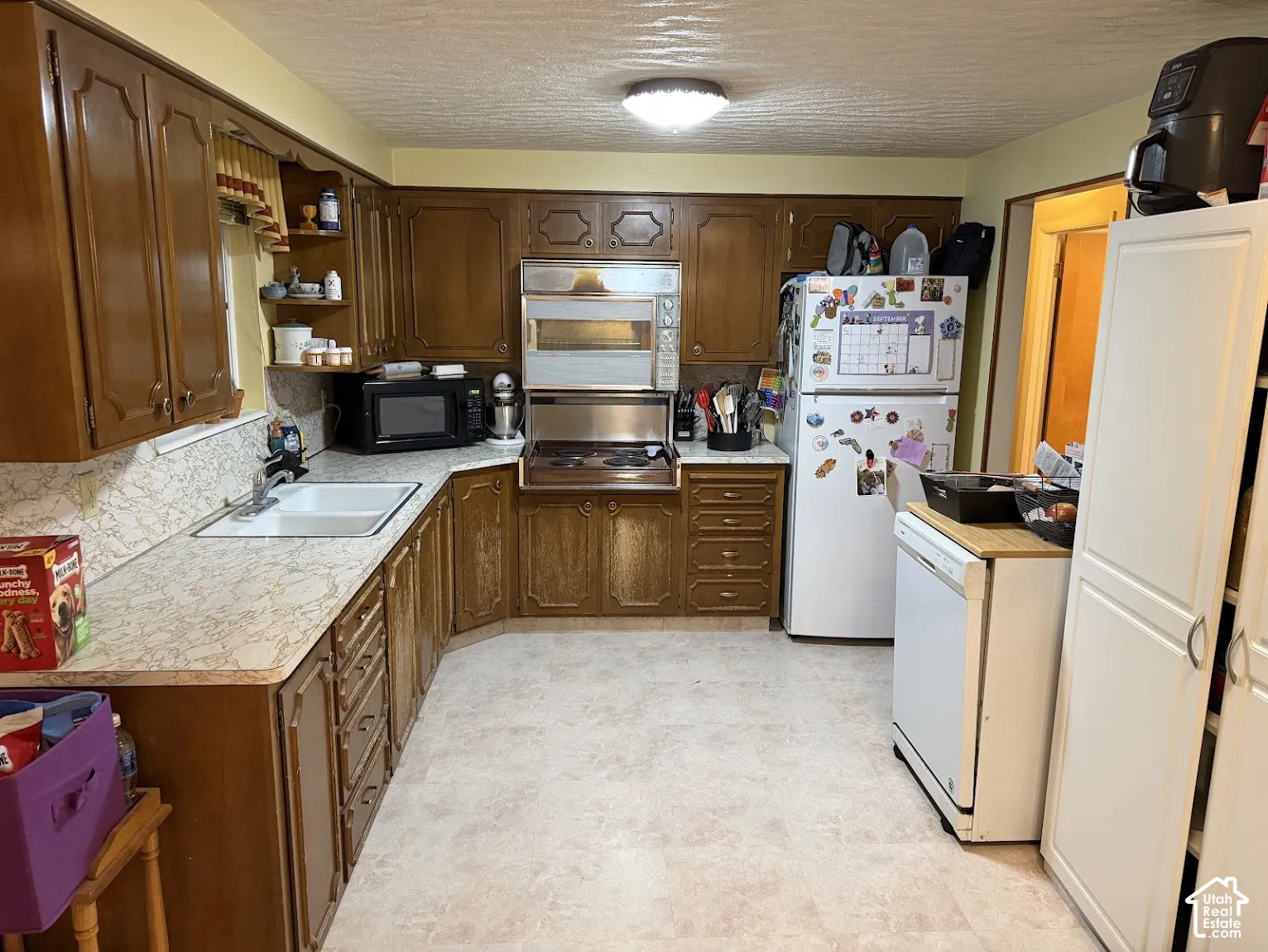 U-shaped kitchen with wood-finish cabinetry, built-in wall oven, and light-toned countertops