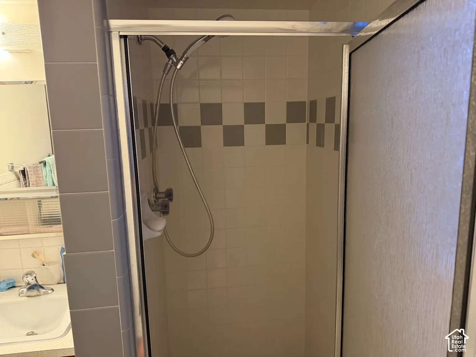 Tile-surrounded shower enclosure with a checkered accent band and a frosted glass door