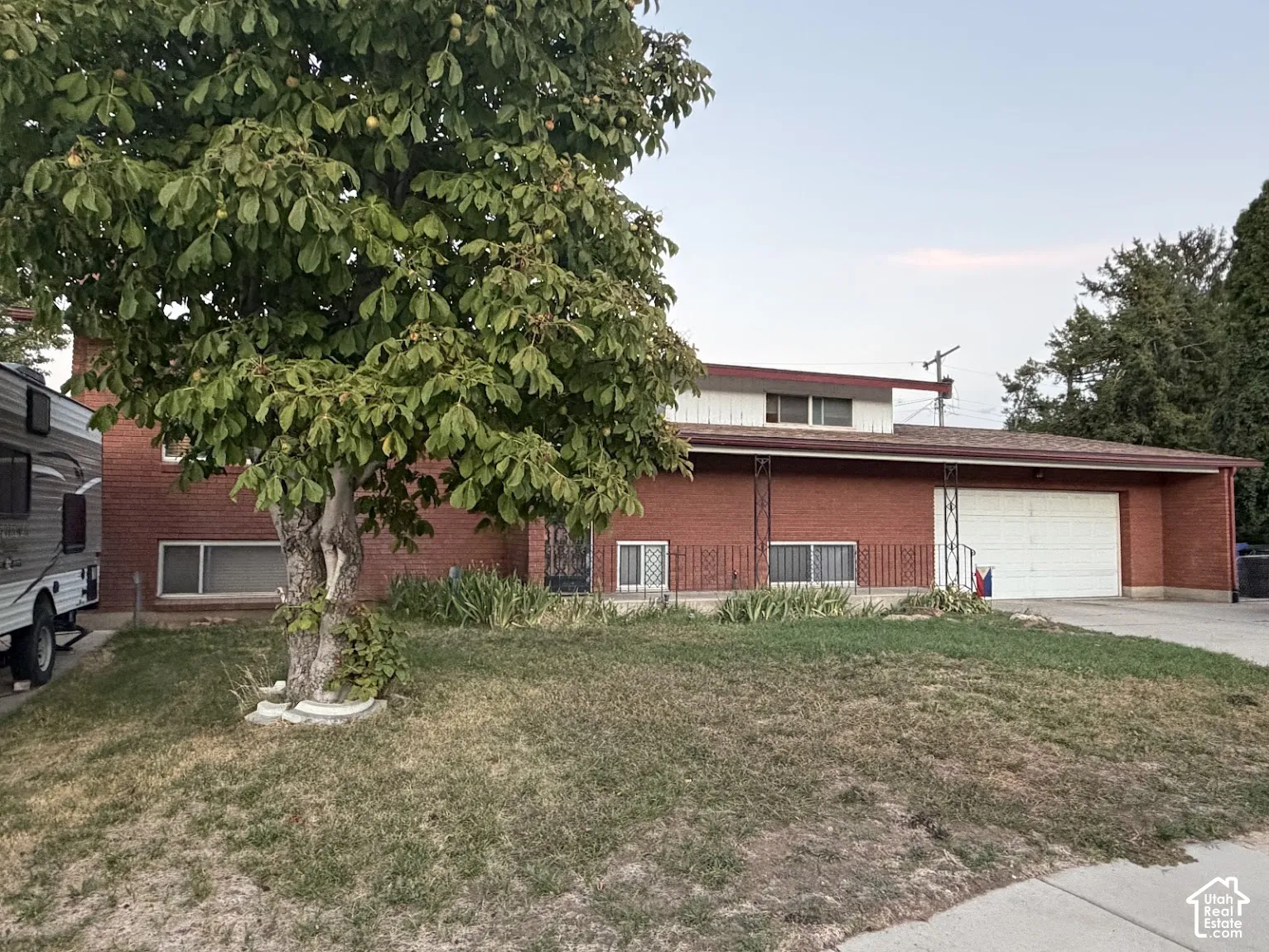 Brick exterior with a prominent mature tree, providing a shaded front yard