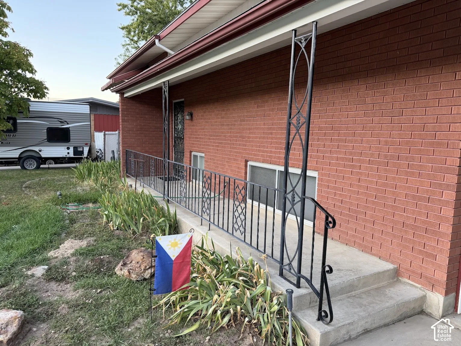 Brick exterior featuring a concrete porch with decorative wrought iron railings