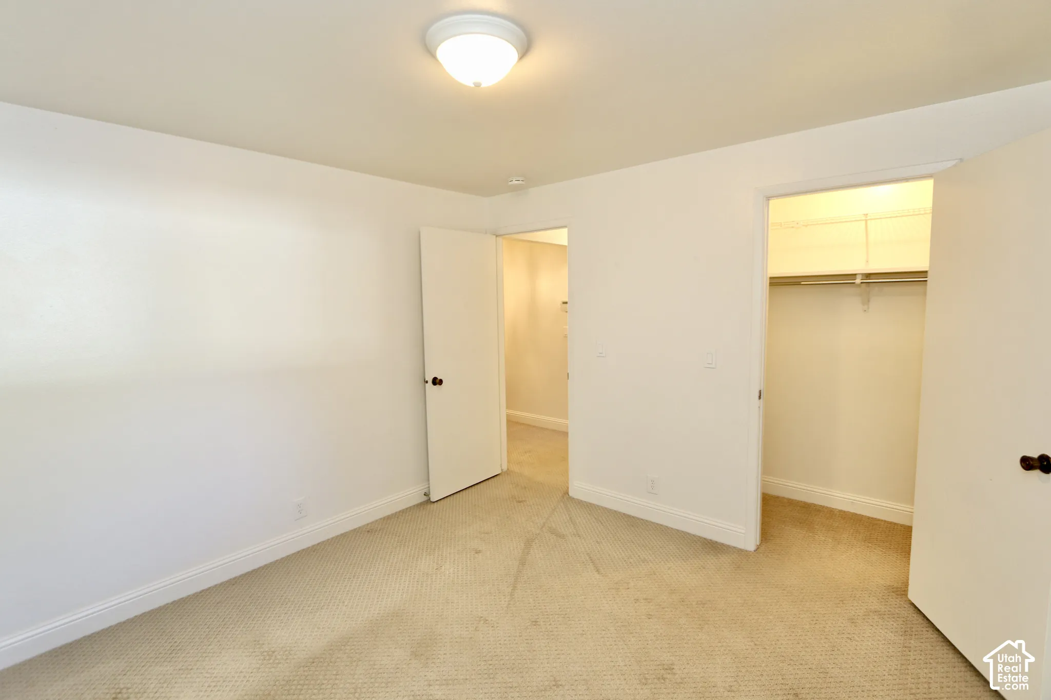 2nd bedroom with neutral wall finishes, flush-mount ceiling light, carpet flooring, open closet with wire shelving, and white baseboards