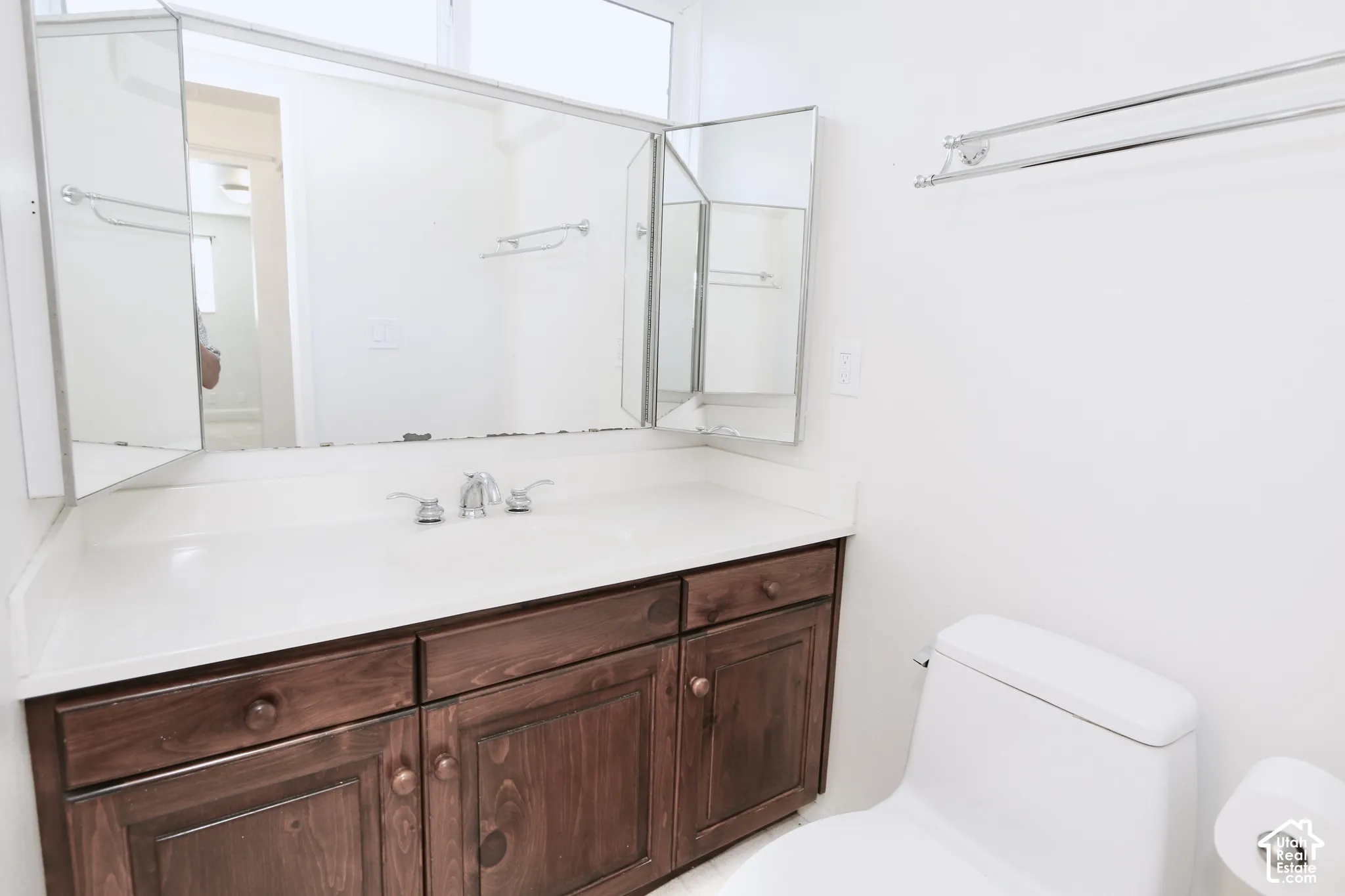 Master bathroom: White vanity countertop with an integrated sink, polished chrome faucet, dark wood-finish cabinetry, and a tri-fold medicine cabinet