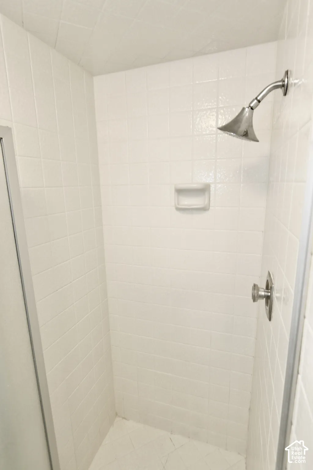 Master bathroom with white tiled shower enclosure with a brushed metal shower head and control