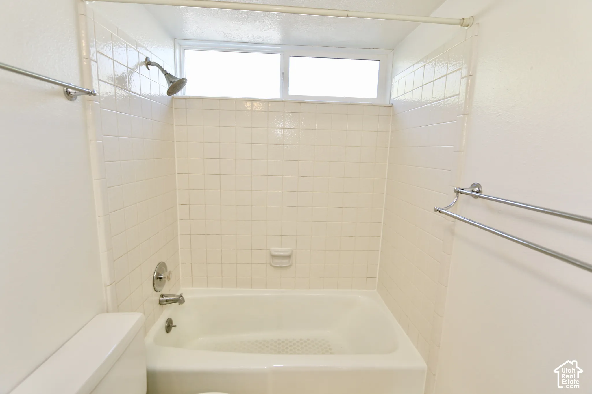 2nd bathroom bathtub with ceramic tile surround, integrated soap dish, and an overhead window