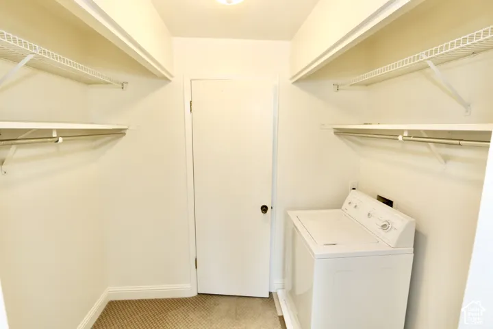 Master closet with laundry area featuring a top-load washing machine, built-in wire shelving, and carpeted flooring