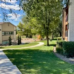 Manicured lawn with mature trees and paved walkways, complemented by brick and siding exteriors