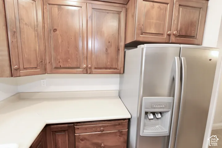 Wood-finish cabinetry, light-toned countertops, and a stainless-steel refrigerator with an external ice and water dispenser