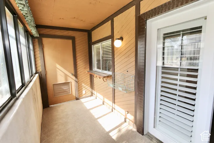 Enclosed porch with full-lite windows, wall-mounted light fixture, and textured wall paneling