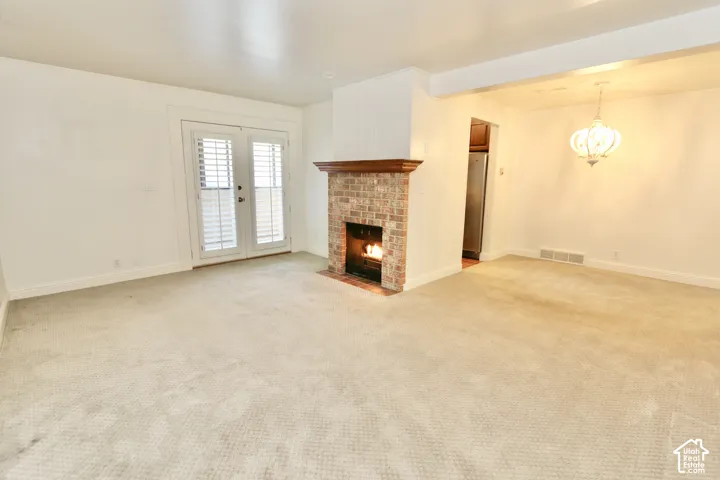 Brick fireplace with wood mantel, white paneled double doors, and a decorative chandelier