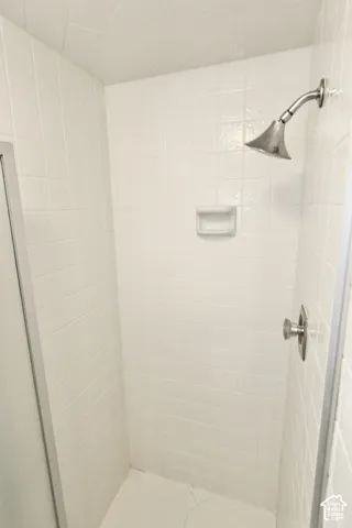 Master bathroom with white tiled shower enclosure with a brushed metal shower head and control