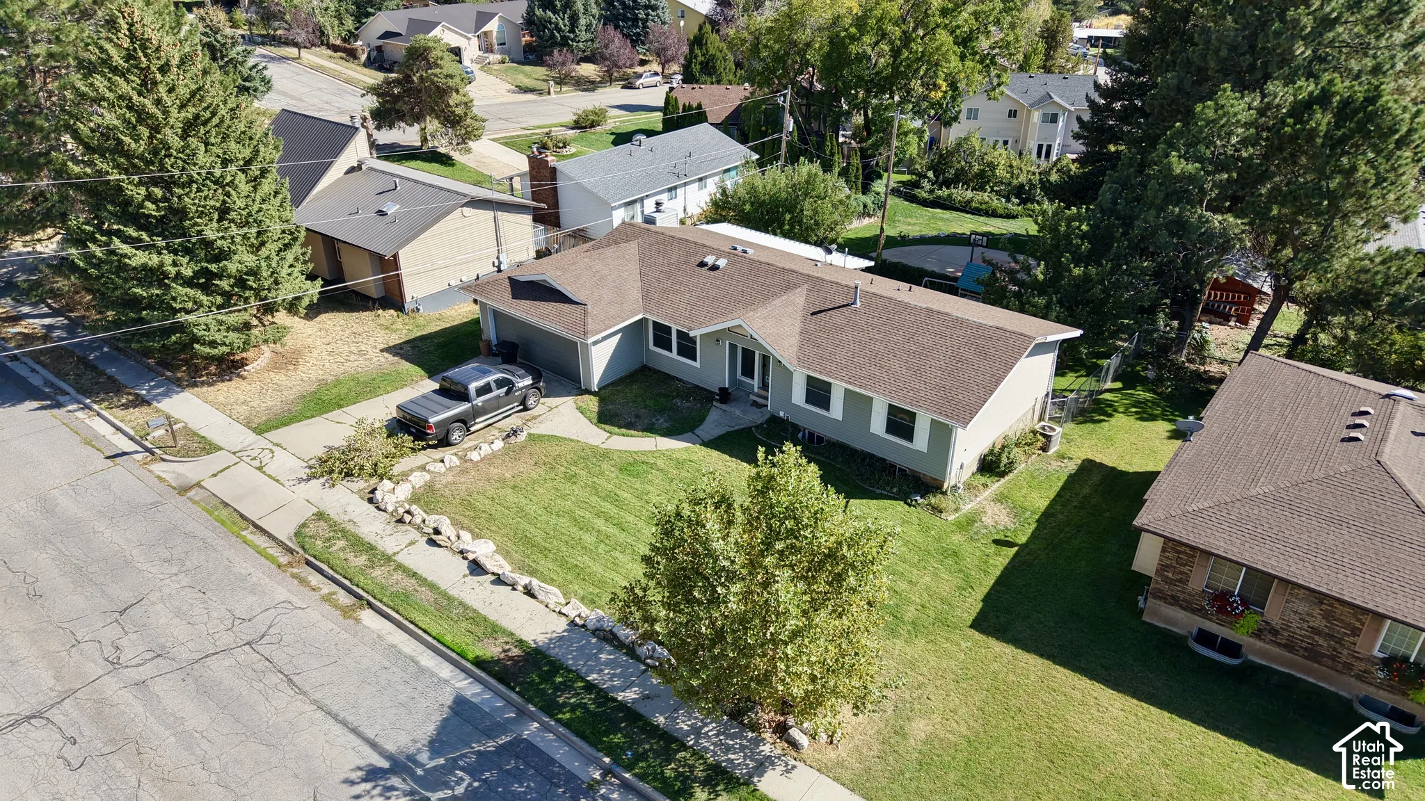 Single-story residence featuring light gray siding, an attached garage, and a brown shingle roof