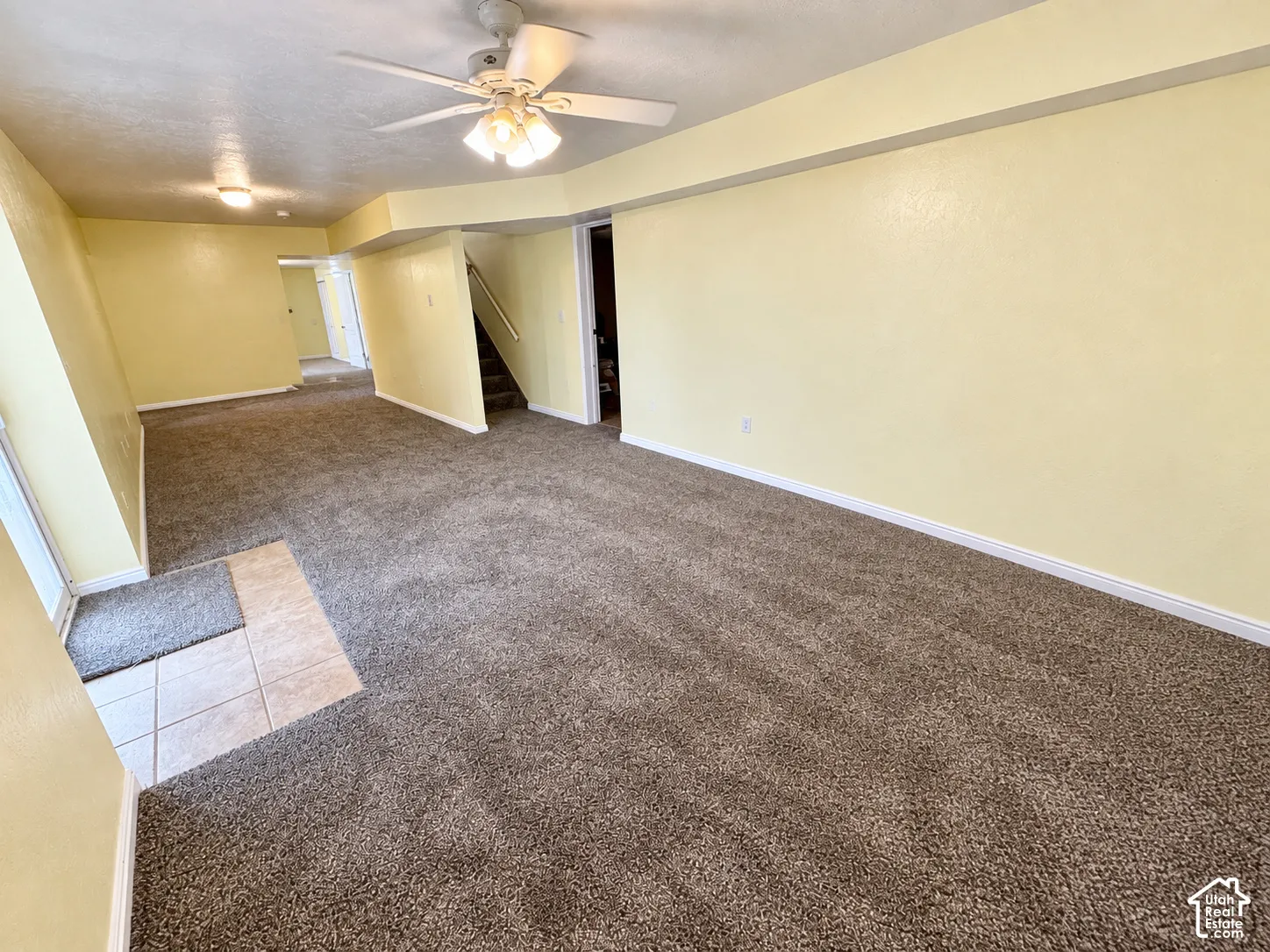 Spacious room featuring broadloom carpeting, a tile entry, a ceiling fan with integrated lighting, and recessed lighting