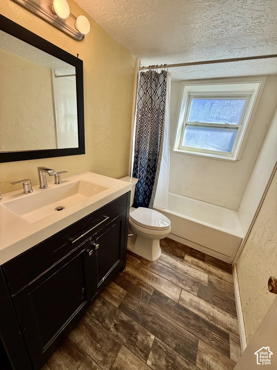 Bathroom featuring a dark wood-finish vanity with an integrated sink, modern chrome faucet, and wood-finish flooring