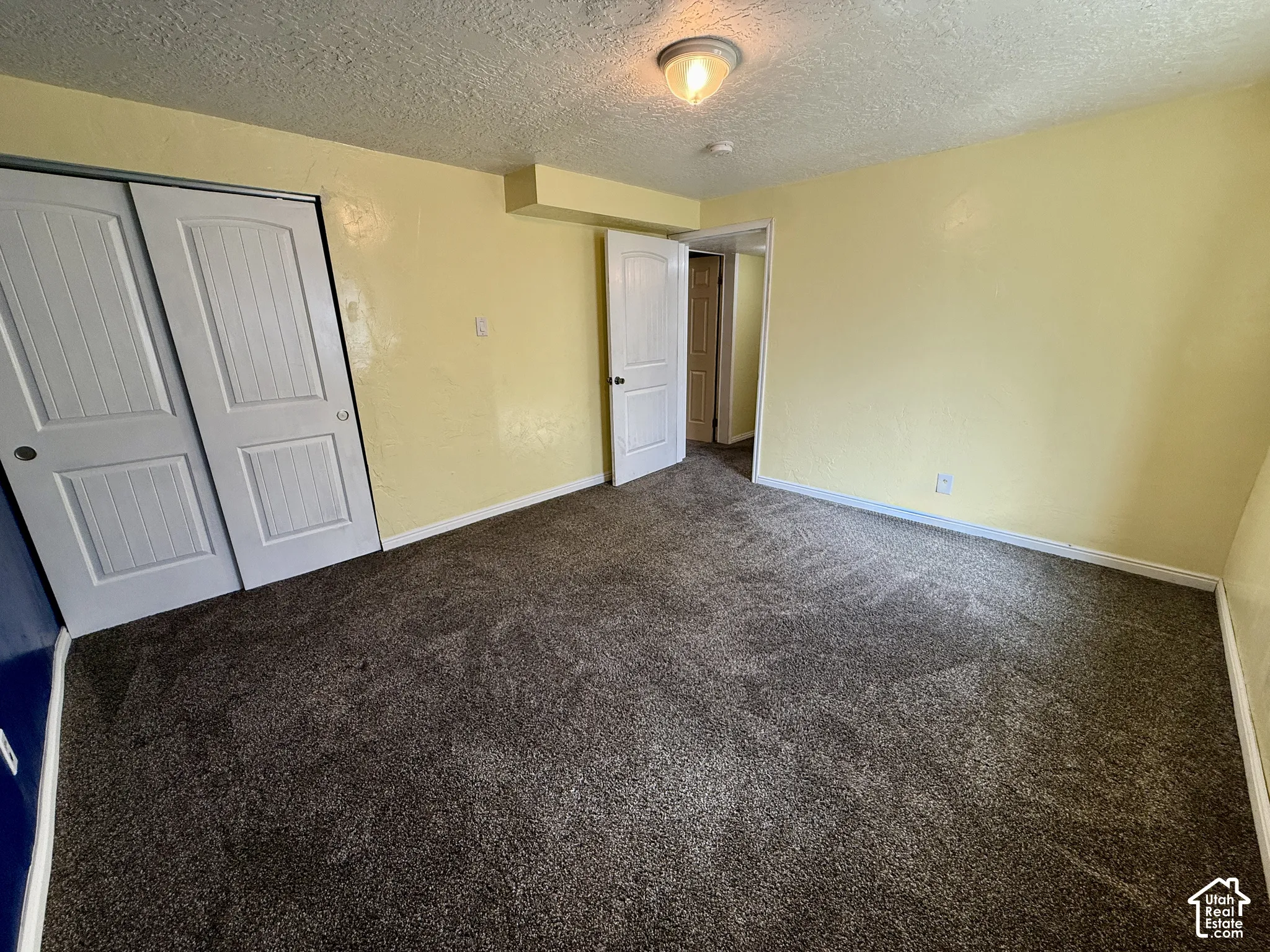 Neutral-toned carpeting, white trim, interior door, and a built-in closet with sliding panel doors