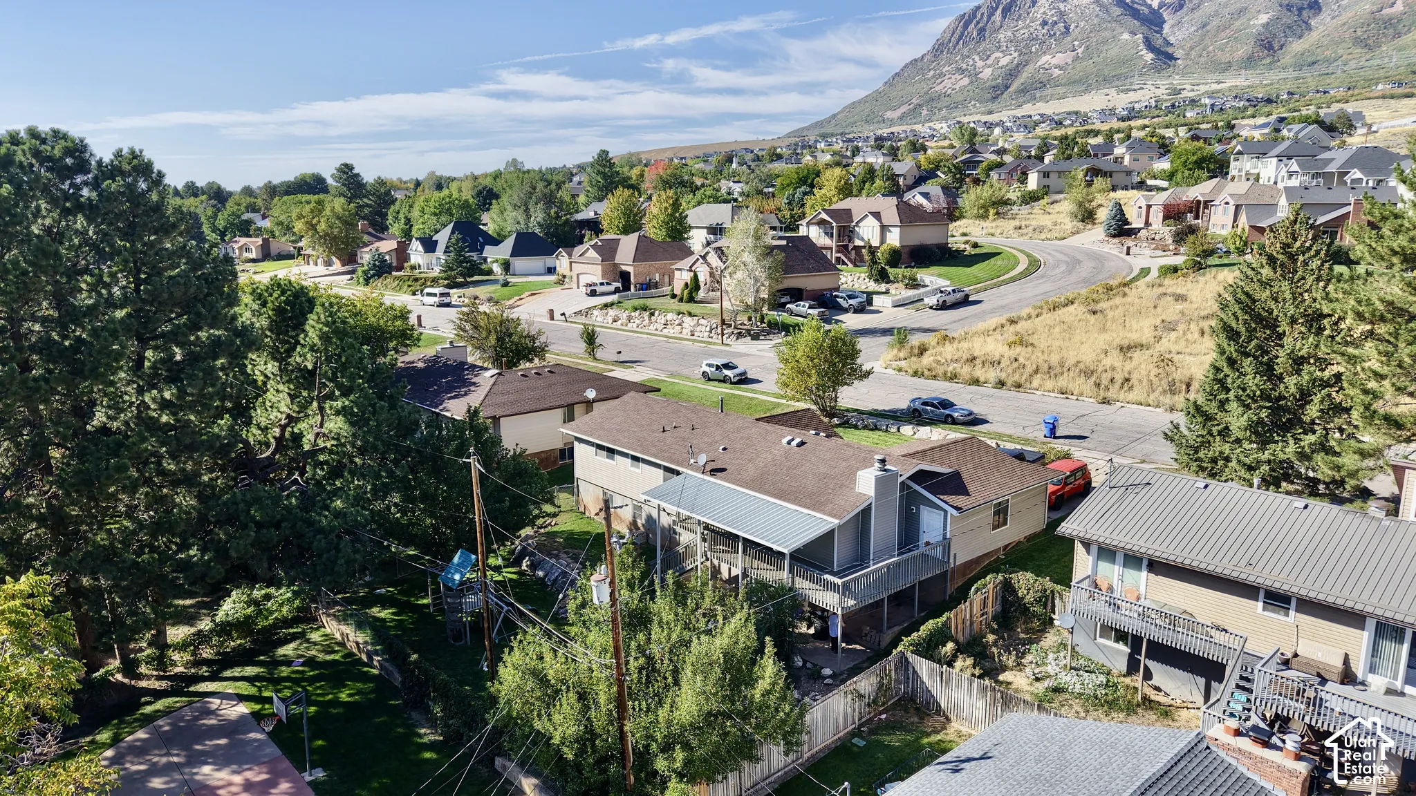 Residential neighborhood with mature trees, paved streets, and mountain backdrop