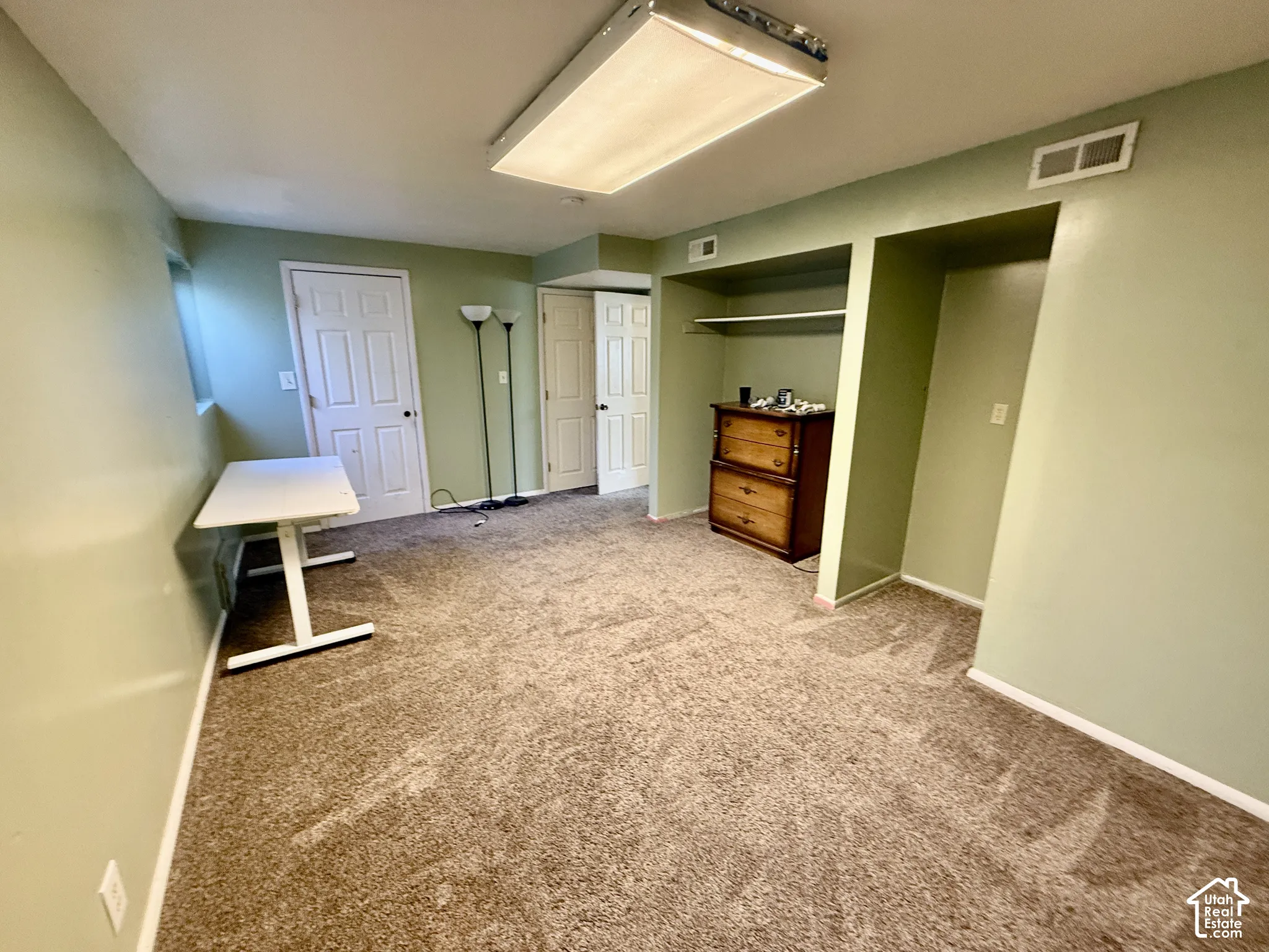 Recessed lighting, light green painted walls, neutral carpet flooring, and white trim
