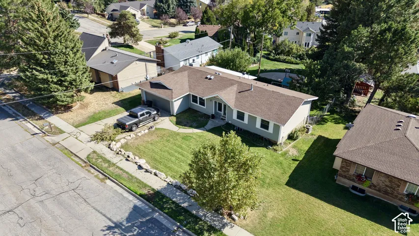 Single-story residence featuring light gray siding, an attached garage, and a brown shingle roof