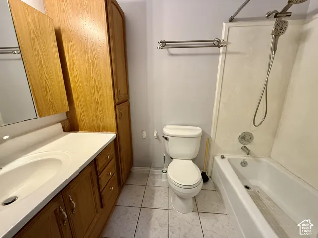 Bathroom featuring a single vanity with wood-finish cabinetry, a built-in medicine cabinet, a full bathtub with shower, a toilet, and tiled flooring