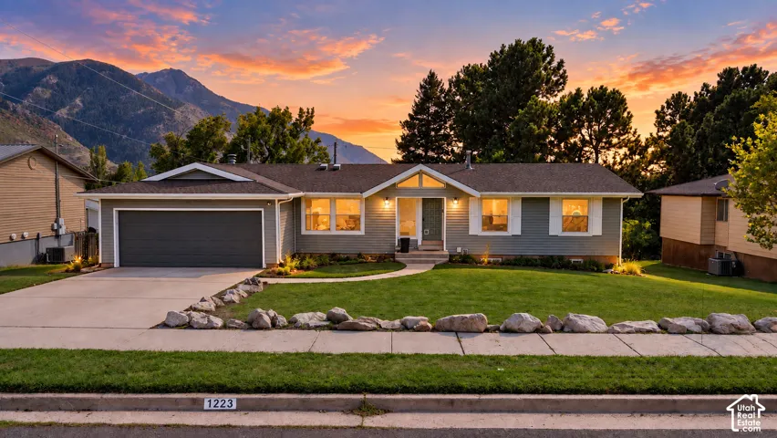 Single-story residence featuring a gray exterior, a two-car garage, and a manicured lawn