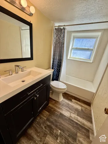 Bathroom featuring a dark wood-finish vanity with an integrated sink, modern chrome faucet, and wood-finish flooring