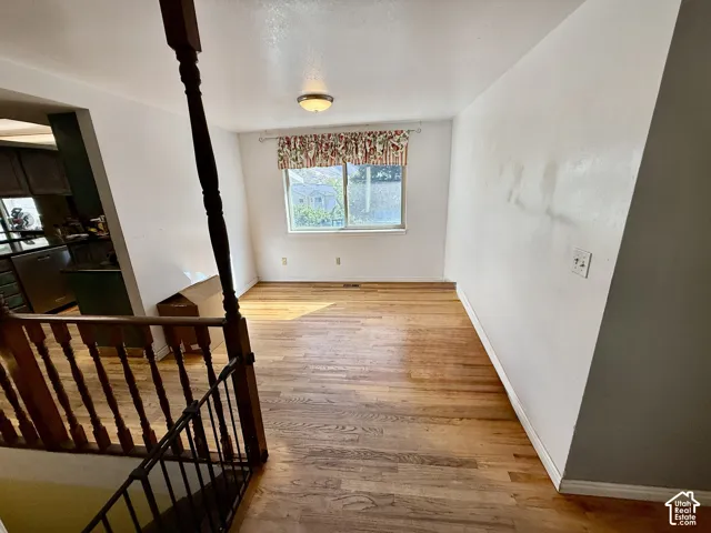 Wood-finish flooring with white baseboards, a window with valance, and a ceiling-mounted light fixture