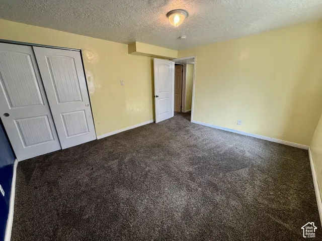 Neutral-toned carpeting, white trim, interior door, and a built-in closet with sliding panel doors