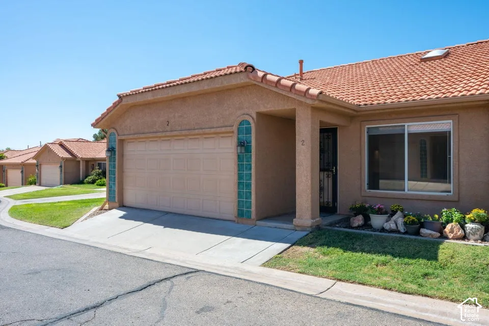 Stucco exterior featuring a terracotta tile roof, attached garage with glass block accents, and a skylight