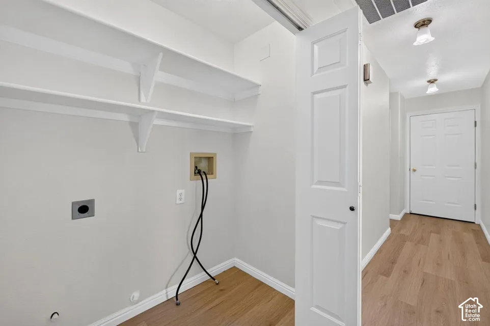 Dedicated laundry area featuring wall-mounted shelving and utility hookups