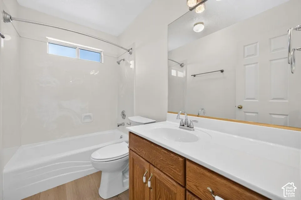 Bright bathroom featuring a vanity with a white countertop, wood-finish cabinetry, a built-in mirror, a full bathtub with shower, and a high window