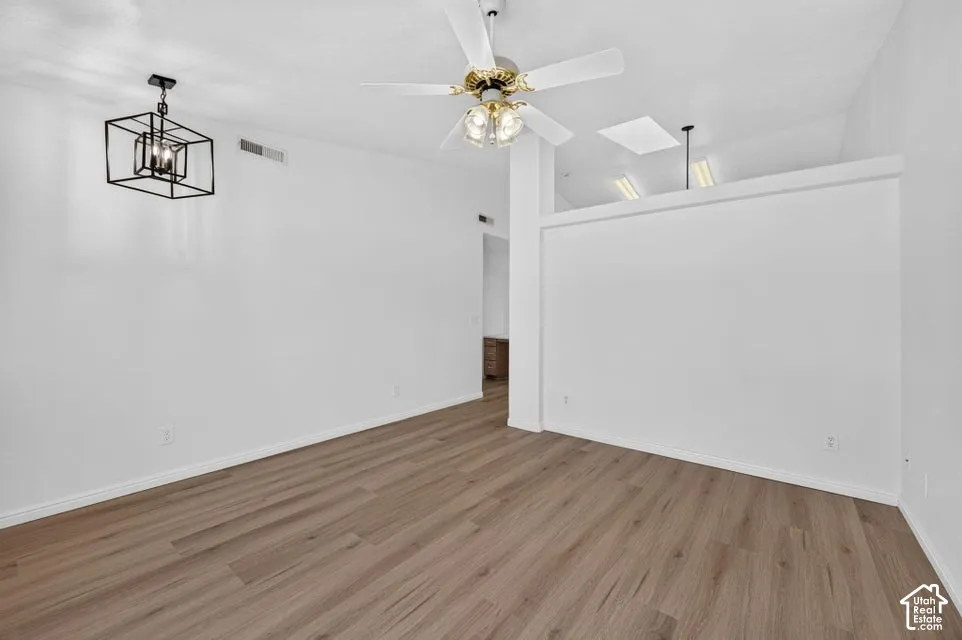 Wood-finish flooring throughout, complemented by a modern geometric chandelier and a ceiling fan