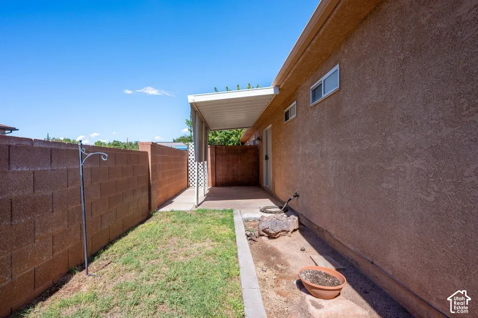 Covered patio area with stucco exterior, block wall fencing, and a grassy yard space