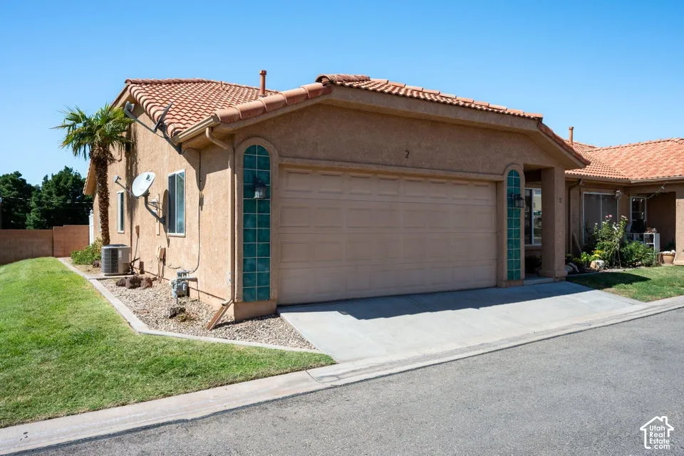 Stucco exterior with a terracotta tile roof, attached garage, and a concrete driveway