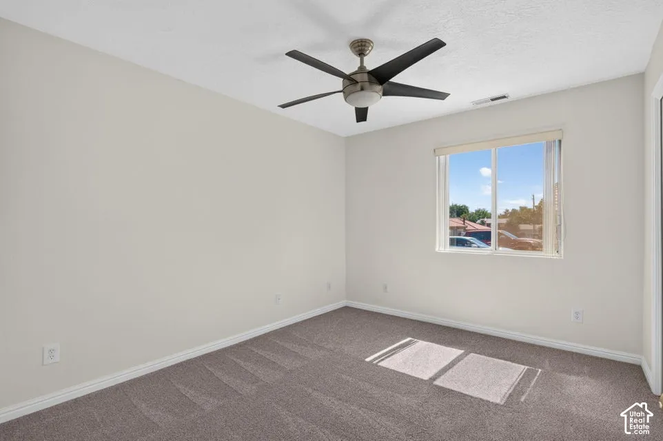 Neutral wall paint, ceiling fan with light fixture, carpeted flooring, and a window with blinds
