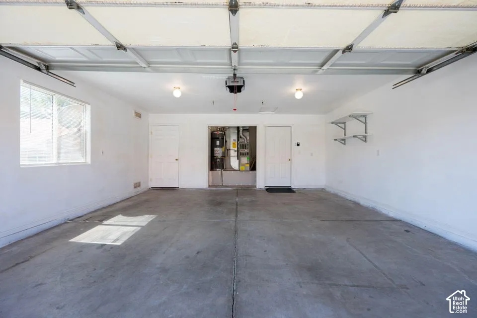 Spacious two-car garage with overhead door mechanism, concrete flooring, and built-in shelving