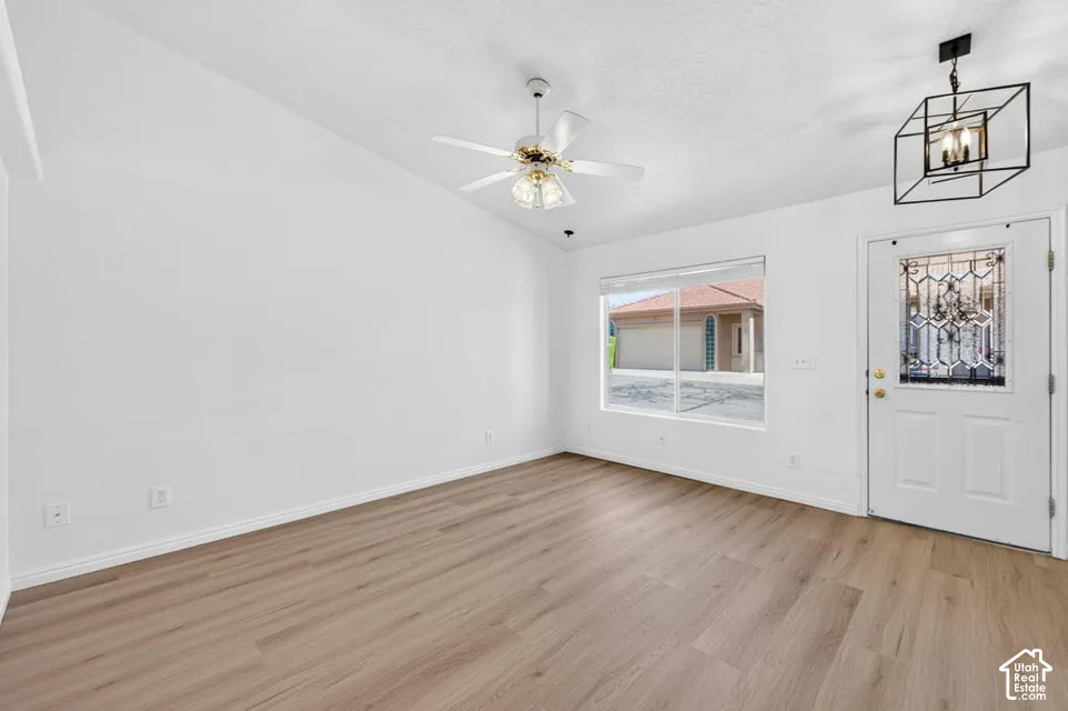 Vaulted ceiling with ceiling fan, wood-finish flooring, and white walls