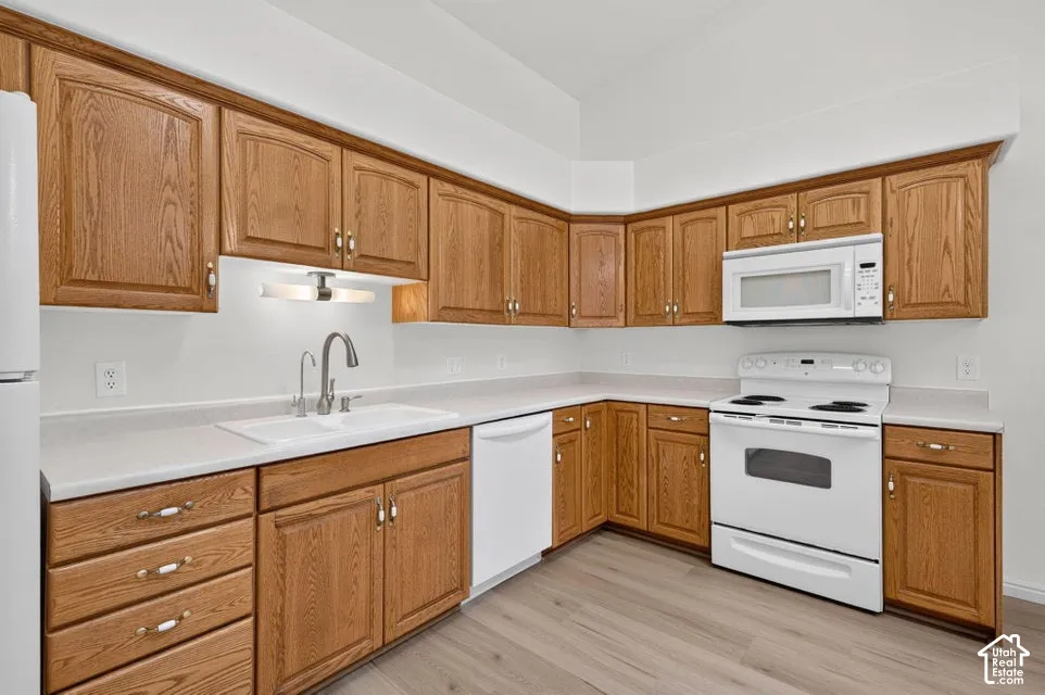 Light wood-finish cabinetry with white countertops, a double basin sink, and a full suite of white appliances