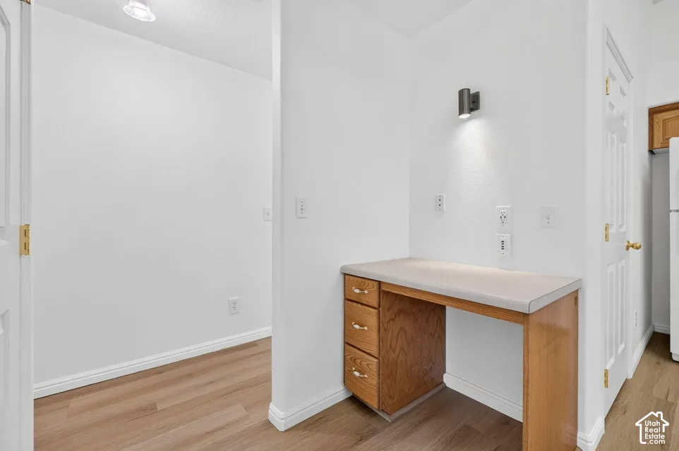 Built-in desk with wood-finish cabinetry, a light-colored countertop, and a wall-mounted fixture