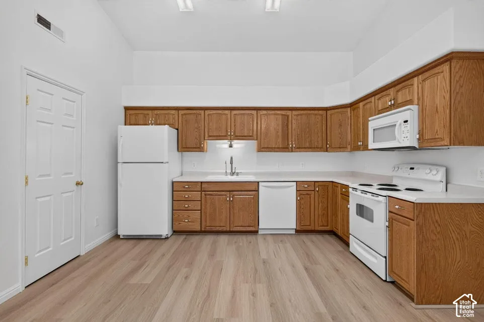 Kitchen featuring wood-finish cabinetry, white countertops, and white appliances