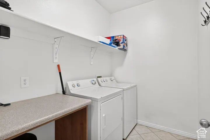 White walls, tiled flooring, built-in shelving, countertop workspace, and coat hooks