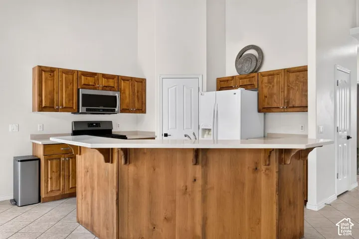 Kitchen featuring a large central island with solid wood paneling, light-toned countertops, and built-in wood cabinetry